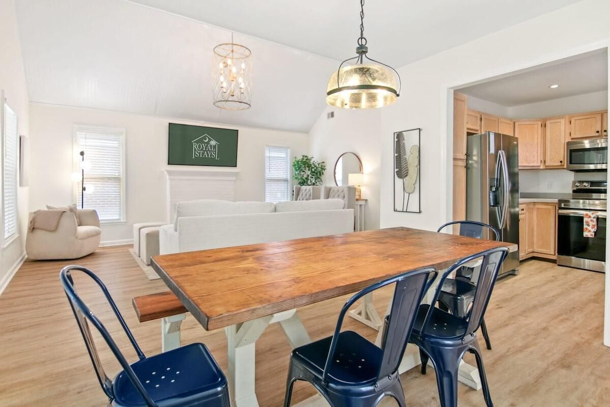 Une cuisine moderne avec des meubles en bois, des appareils en acier inoxydable et un coin repas comprenant une table en bois et des chaises bleues.