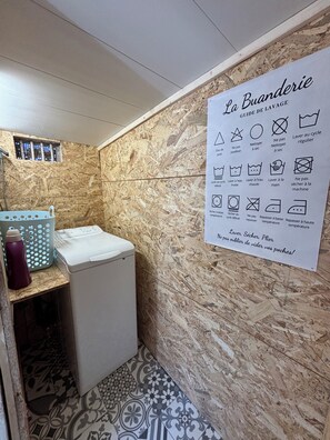 A laundry area with a washing machine, a drying rack, and a sign with laundry instructions. - 3-Star Vacation Rental “La maison de Doris” (Bihorel)