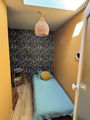 A small bedroom with a single bed, a wall-mounted light fixture, and a patterned wallpaper. - 3-Star Vacation Rental “La maison de Doris” (Bihorel)