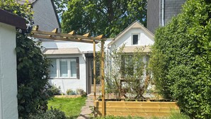 En bostadsfastighet med en täckt uteplats, ett trästaket och en välskött trädgård.