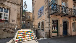 A street with a staircase leading to a building with a sign reading 'l'herbiste.' - Apartment 'La Petite Caille - 5' with Wi-Fi (Plombières-les-Bains)