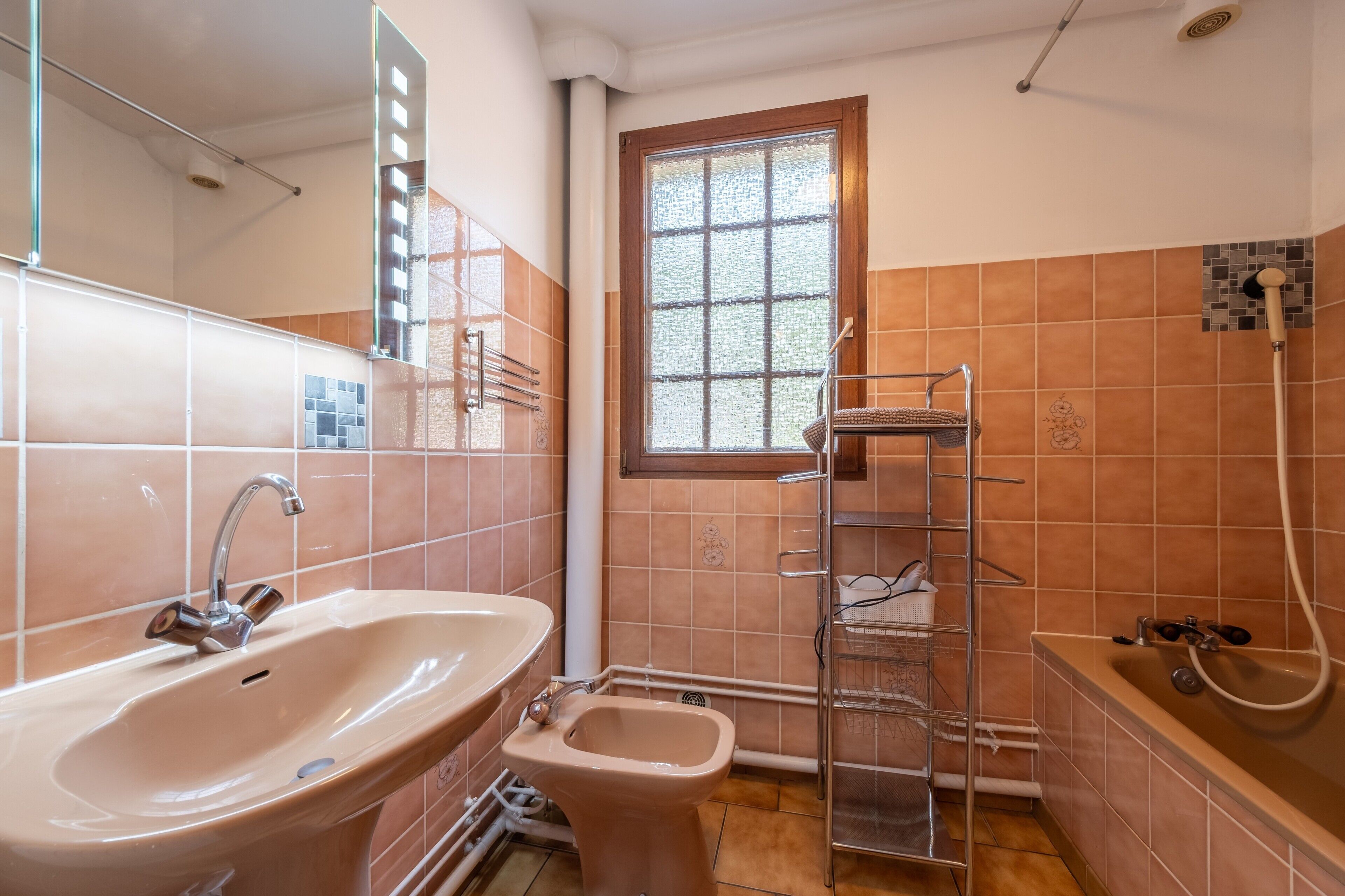 Une salle de bain avec un lavabo, des toilettes, une douche et une fenêtre.
