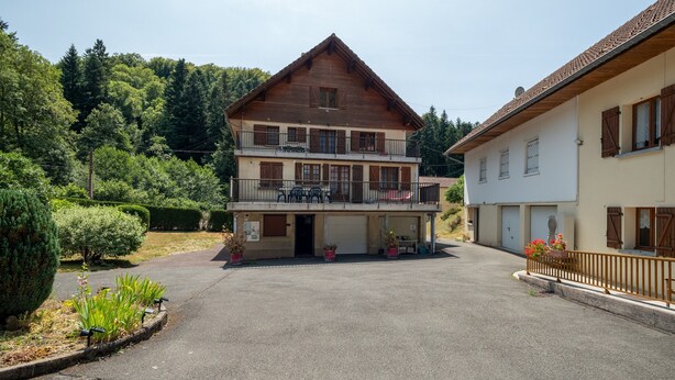 A two-story building with a balcony, a garage, and a paved driveway.