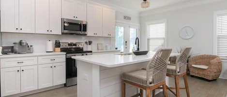 A modern kitchen with white cabinetry, a central island, and bar stools.