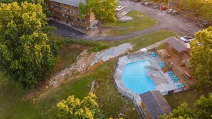Eine Luftaufnahme eines Hotels mit Schwimmbad, Parkplatz und umliegender Bepflanzung.