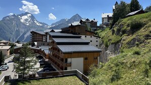 A mountain village with traditional wooden buildings, a road, and a view of snow-capped mountains. - Cabin studio with mountain view (Les Deux Alpes)