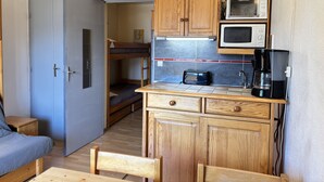 A compact kitchen with wooden cabinets, a microwave, a toaster, and a coffee maker. - Cabin studio with mountain view (Les Deux Alpes)