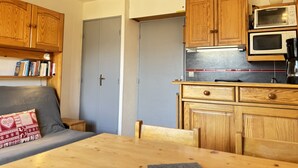 A compact kitchen with wooden cabinets, a microwave, and a coffee maker. - Cabin studio with mountain view (Les Deux Alpes)
