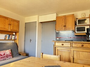 A compact kitchen with wooden cabinets, a microwave, and a coffee maker. - Cabin studio with mountain view (Les Deux Alpes)