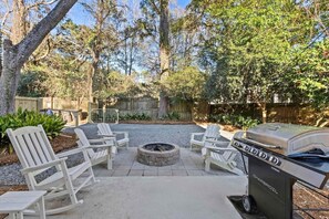 An outdoor patio with Adirondack chairs, a stone fire pit, and a Char-Broil grill. - The Cozy Vibes-6 Beds-fenced in Backyard (Mount Pleasant)
