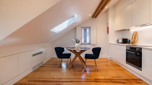 Eine moderne Küche mit Oberlichter, Holzboden und einem Essbereich mit zwei Stühlen.