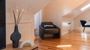 Ein modernes Interieur mit einer gebogenen Bank, einer Vase mit Trockenpflanzen und einem gewölbten Holzelement auf Holzdielen.