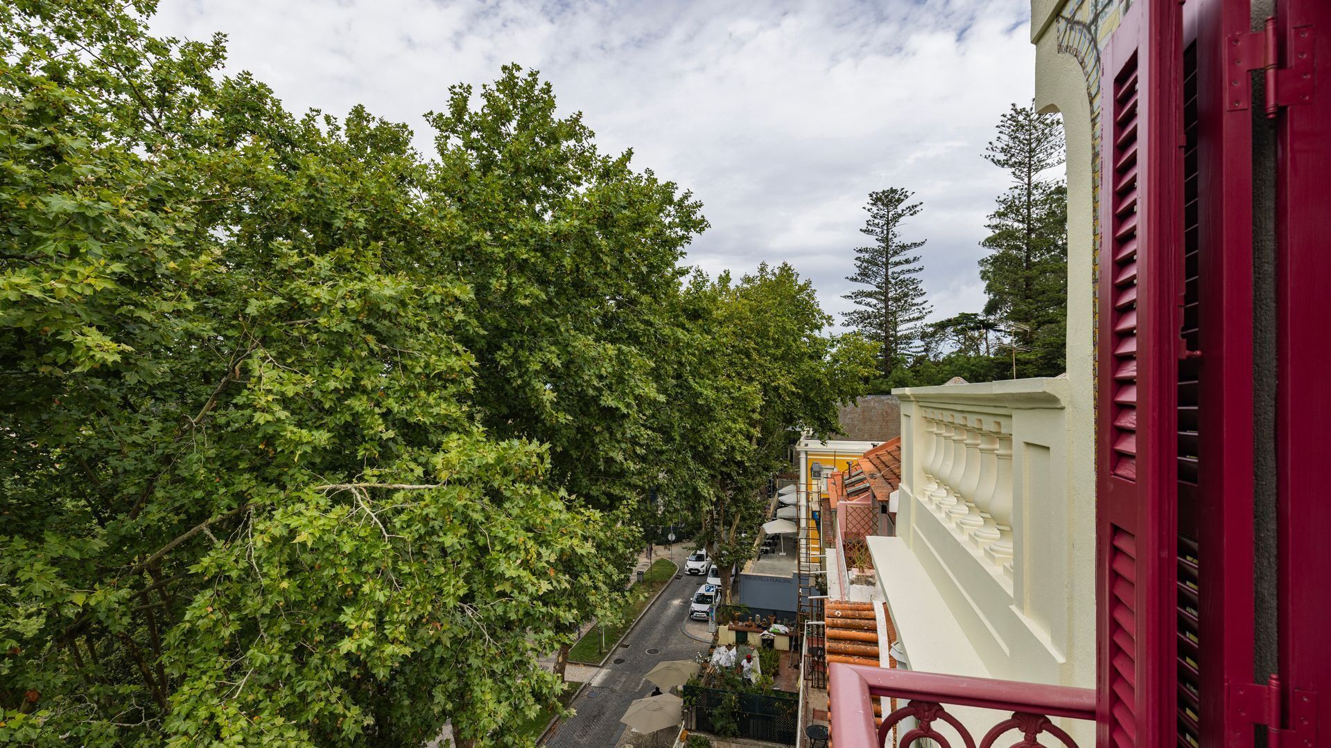 A balcony with a view of a street lined with trees and buildings.