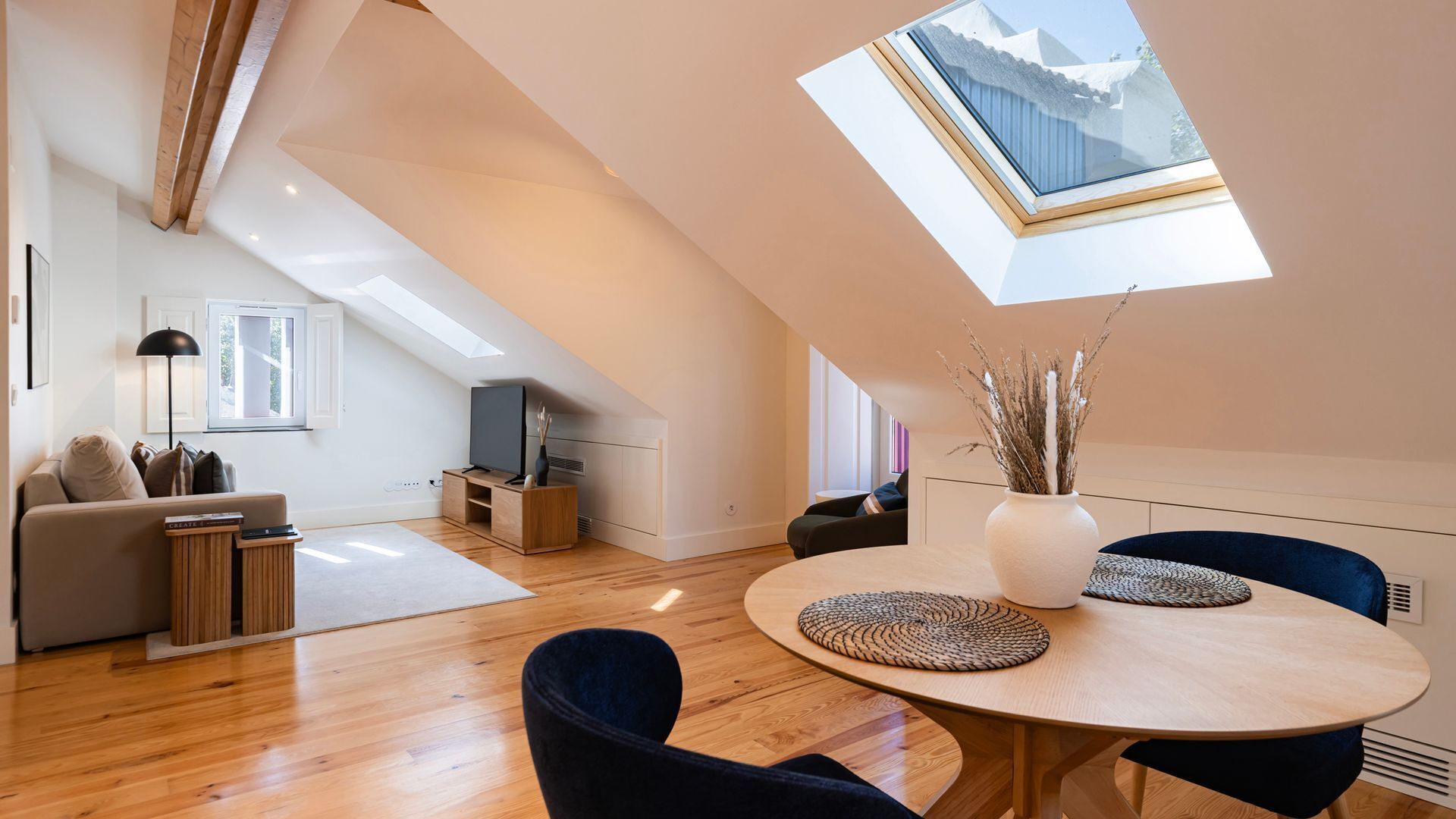 Un appartement moderne de style « loft », doté d’une verrière, de planchers en bois, d’une table de salle à manger ronde et d’un coin salon confortable.