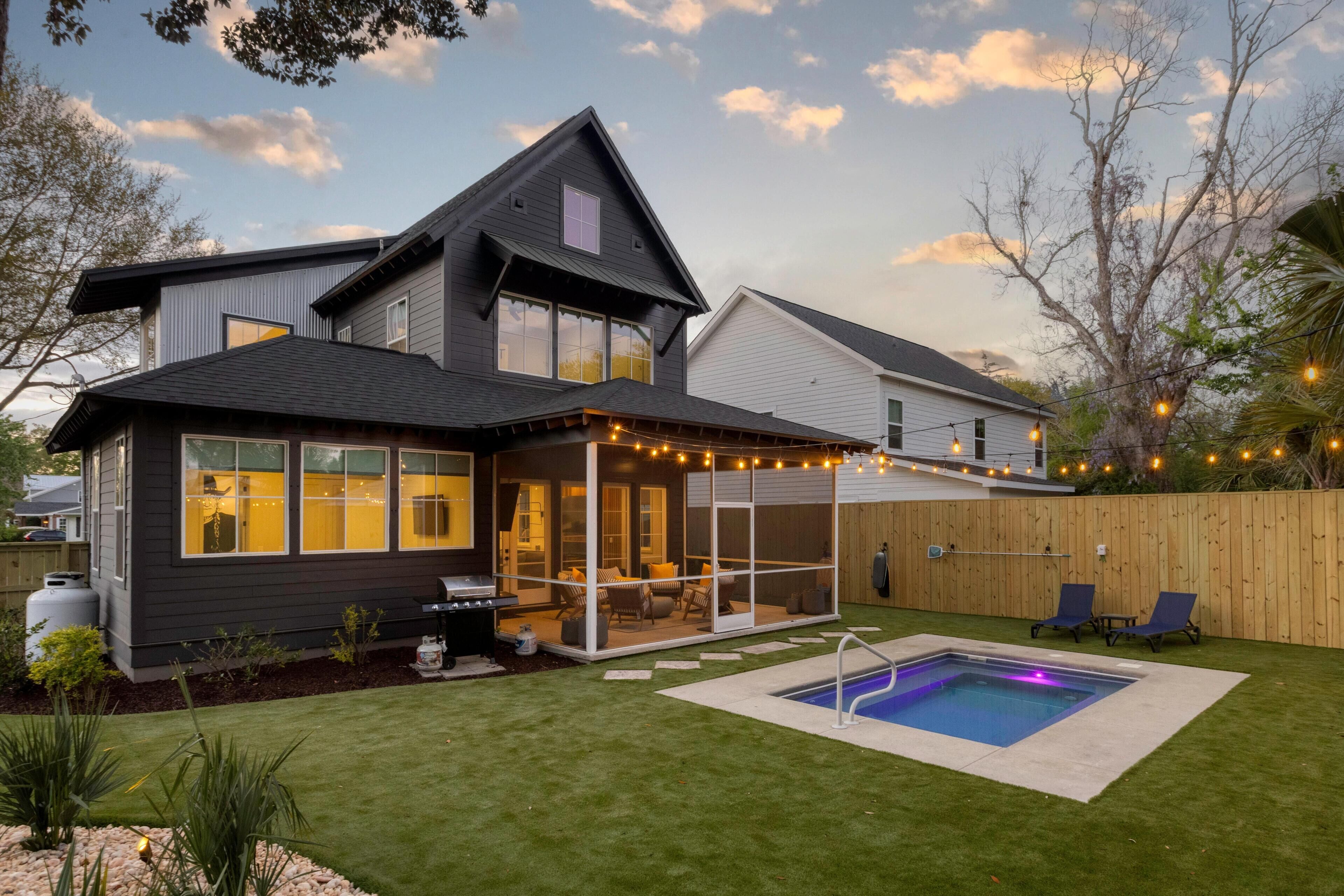 Une maison à deux étages avec un patio, une piscine et des guirlandes lumineuses.