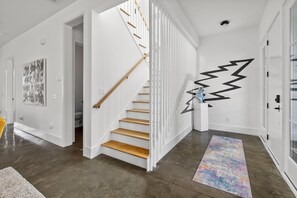A modern interior with a wooden staircase, white walls, and a colorful rug. - Music Manor-3-king Beds-pool-mins To Beach & DT (Mount Pleasant)