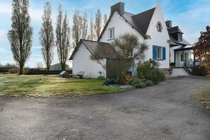 A white house with a grey roof, a gravel driveway, and a garden with various plants and a bench. - La Mainguy Guest Rooms (Ruca)