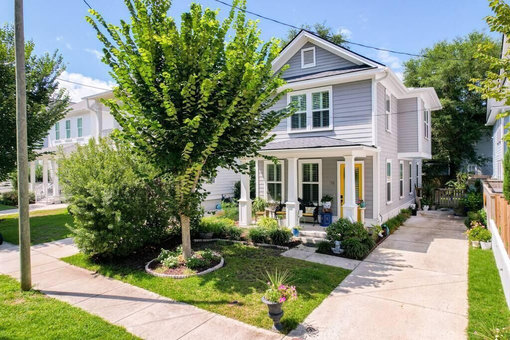 A two-story house with a front porch, a small garden, and a visible garage.