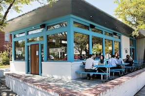 An outdoor seating area with blue benches and a covered structure with large windows. - Holy City Charm-mins To Dtwn-beach & Shem Creek (Mount Pleasant)