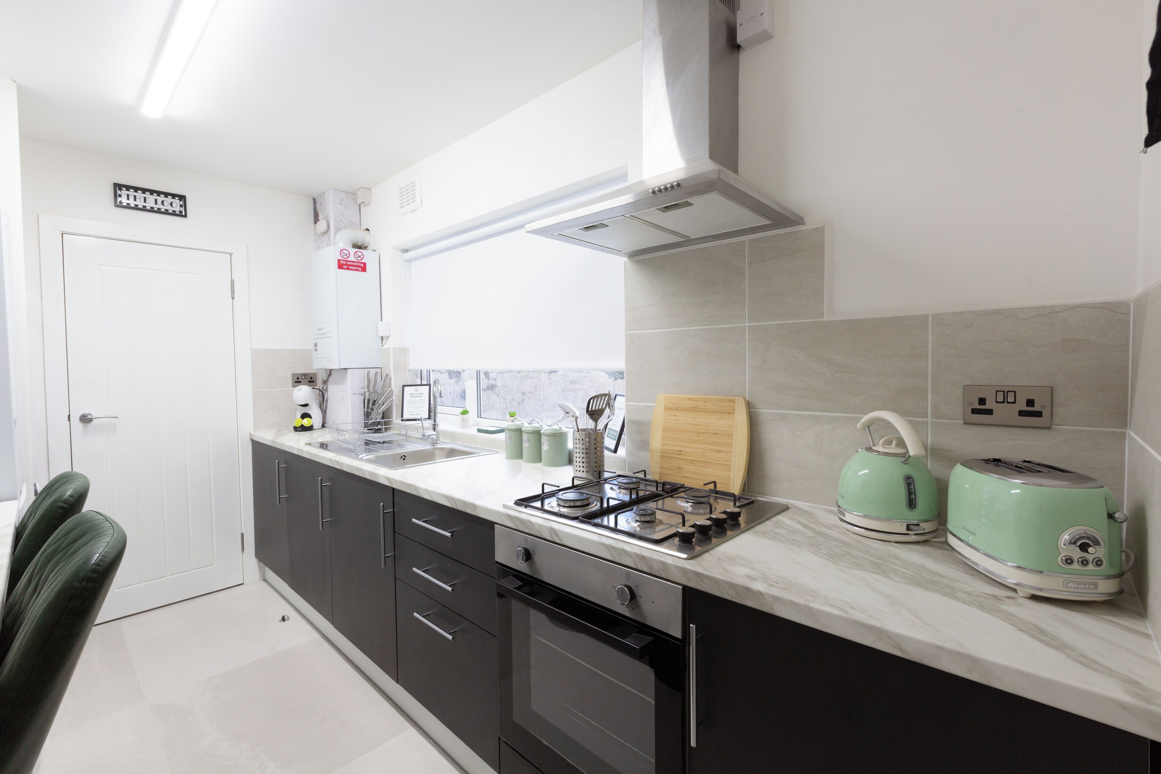 A modern kitchen with a gas stove, a toaster, and a kettle.