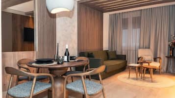 A modern living room with a round dining table, two sofas, and a TV mounted on the wall.
