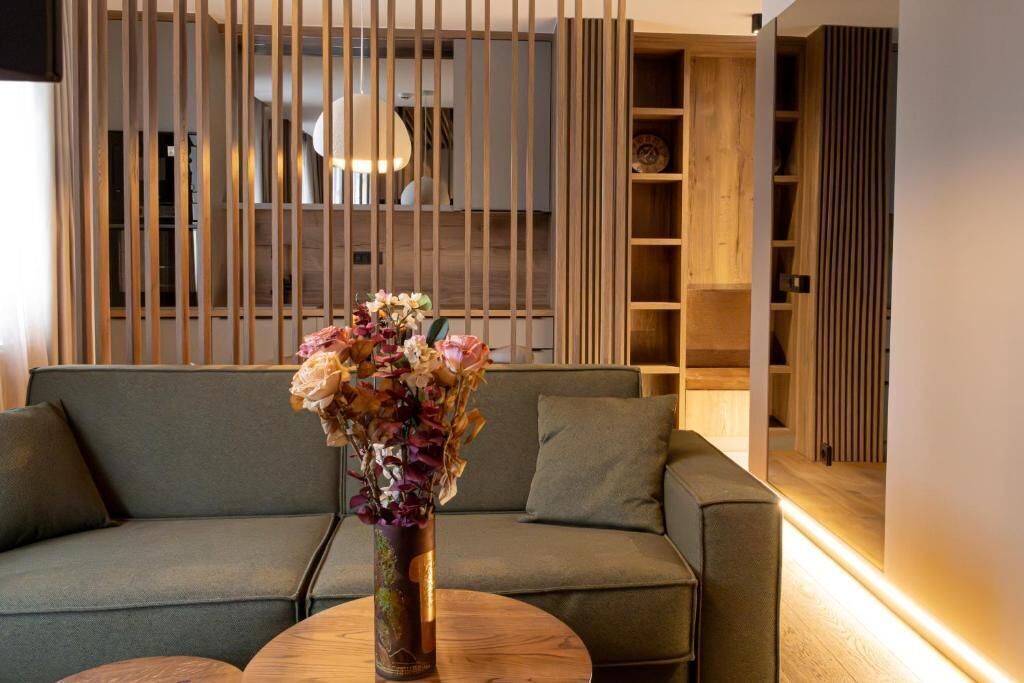A modern living room with a sofa, a round wooden coffee table, and a vase with flowers.