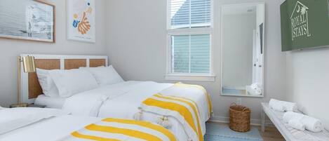 Habitación de hotel con dos camas, un espejo grande, una cesta de mimbre y un banco con toallas.