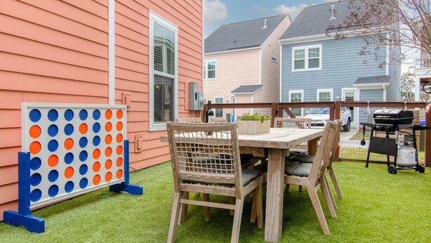 A patio with a wooden table and chairs, a grill, and a game board. - Happy Ours, Mins to Park Circle, Dtwn, CHS Beach (North Charleston)