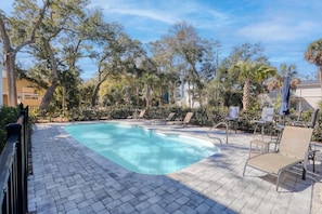 A swimming pool with lounge chairs and a paved deck, surrounded by trees and a fence. - Jungle House-heated Pool-pet Friendly-luxury (Edisto Island)