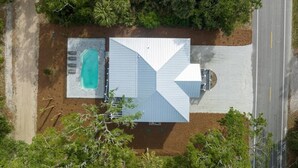 An aerial view of a property with a swimming pool, a covered patio, and a road adjacent to it. - Jungle House-heated Pool-pet Friendly-luxury (Edisto Island)