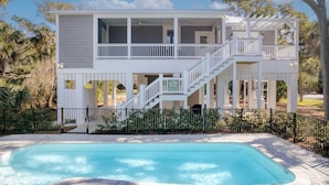 A two-story house with a balcony, a swimming pool, and a fenced yard. - Jungle House-heated Pool-pet Friendly-luxury (Edisto Island)