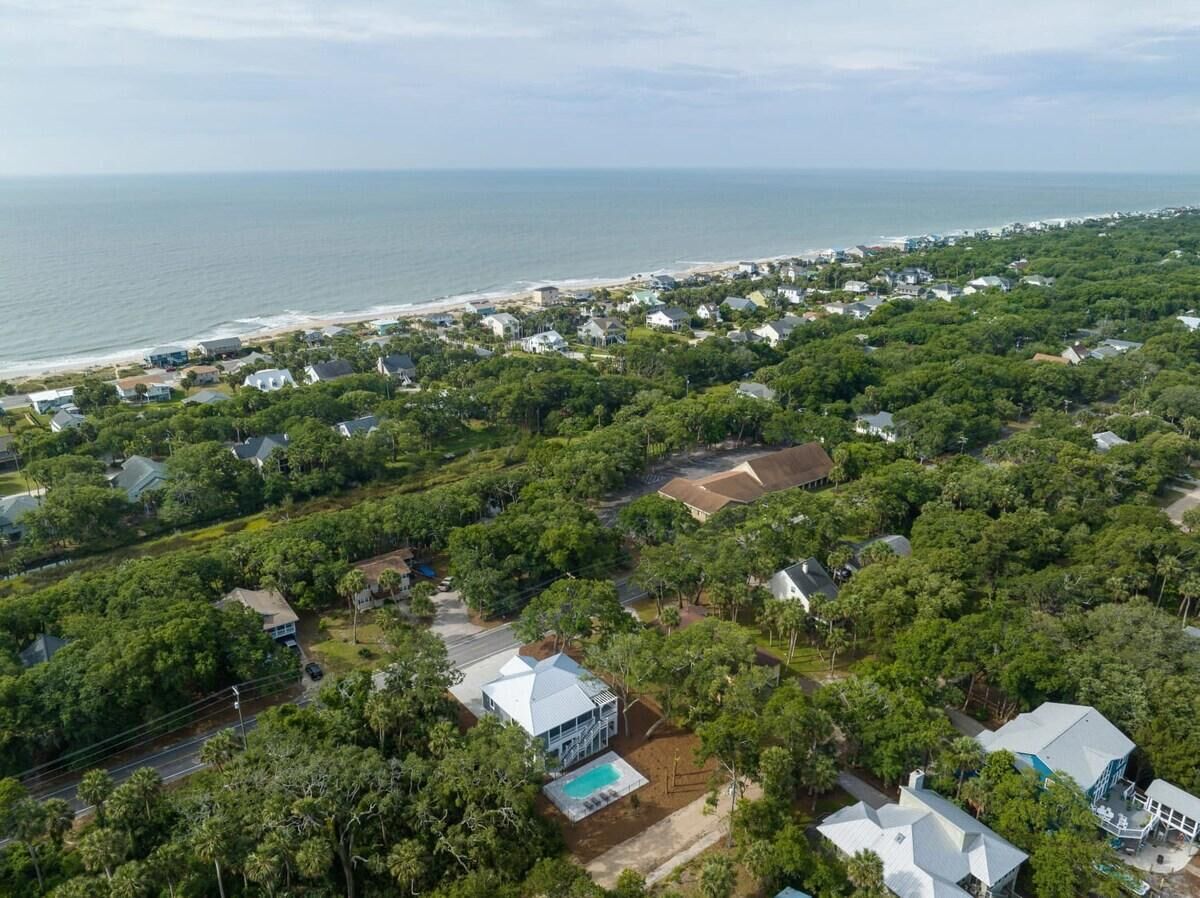 An aerial view of a coastal residential area with houses, a beach, and a clear sky.