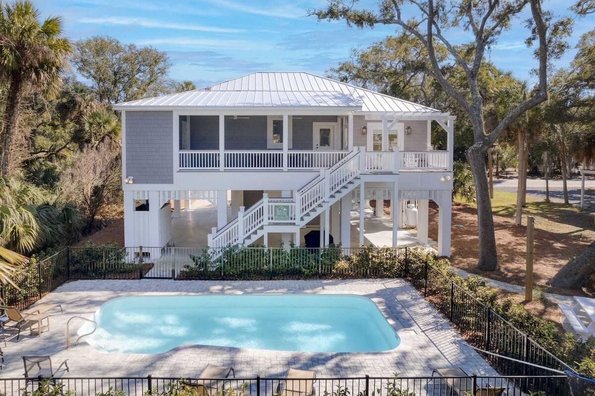A two-story house with a balcony, a pool, and a staircase leading to the upper level.