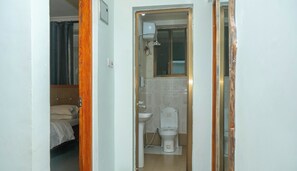 A small bathroom with a toilet, sink, and shower. A bed is visible in the adjacent room. - Marvelous first floor 2-bedrooms apartments in Arusha perfect for your stay (Arusha)