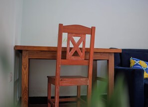 Una silla de madera con respaldo y asiento, ubicada frente a una mesa.
