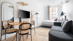 A modern living room with a sofa, a dining table with chairs, a TV, and a window with curtains. - Lapa Diplomatic Collection by Feel Lisboa (Lisbon)