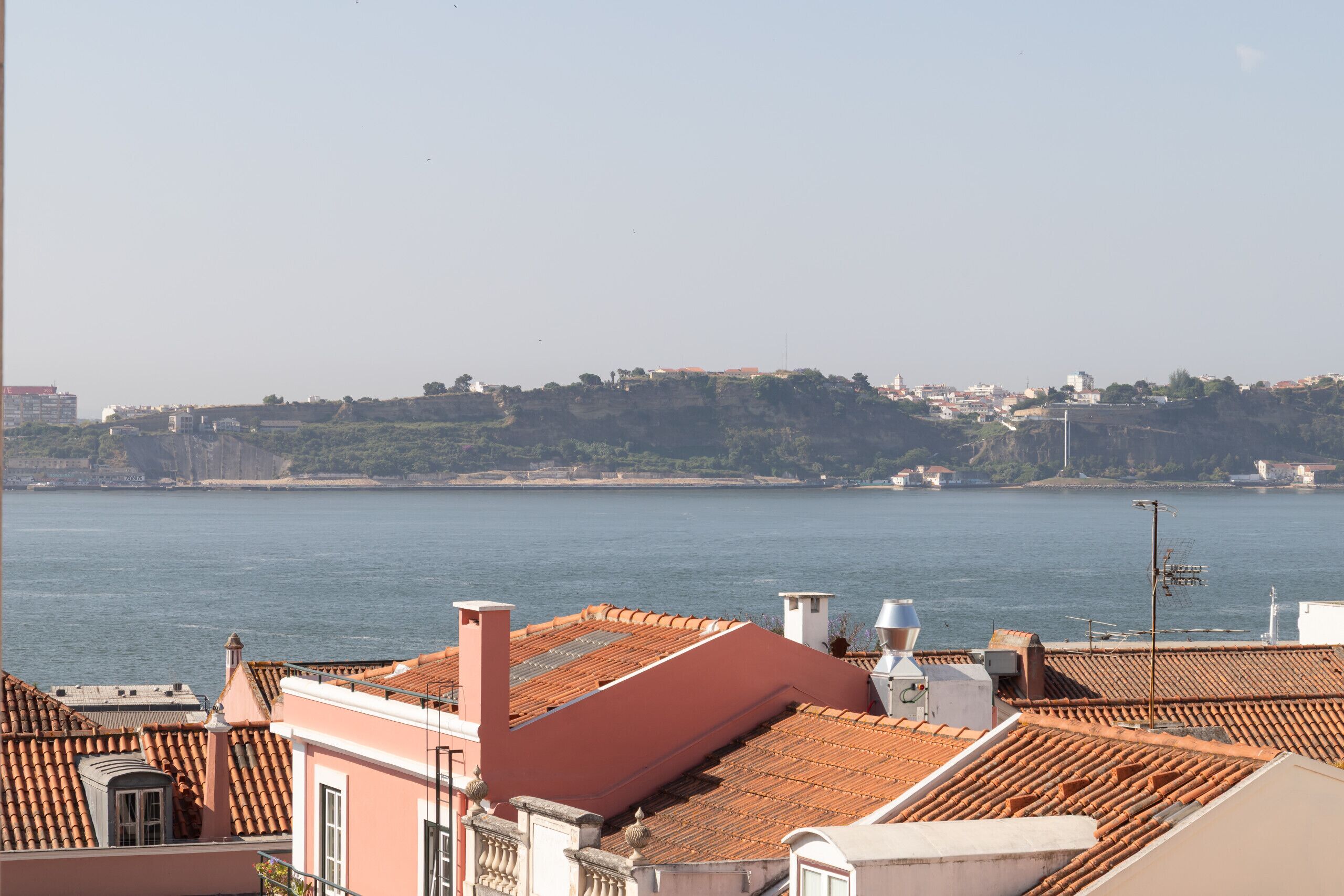 A coastal cityscape with terracotta rooftops and a view of the sea.
