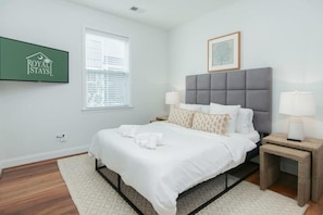 Habitación de hotel con una cama, una mesita de noche con lámpara, un cuadro en la pared y un cartel de Royal Stays.