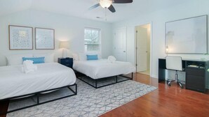 A hotel room with two beds, a desk, a chair, a ceiling fan, and two framed pictures on the wall. - The Jade, Park Circle, Mins to Dwtn and Beaches (North Charleston)