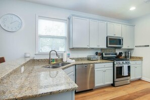 Una cocina moderna con encimeras de granito, electrodomésticos de acero inoxidable y armarios blancos.