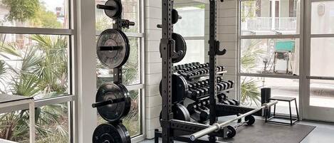 Ett gym med en knäböjsställning, en bänkpress och olika viktskivor.