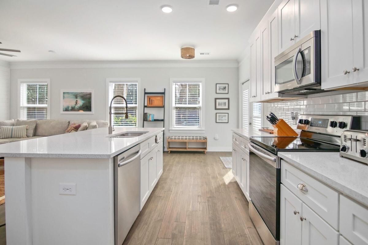 A modern kitchen with white cabinetry, a central island, and a built-in oven.