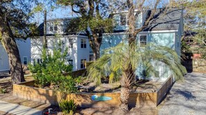 Una zona residencial con una casa, un pequeño jardín y una palmera.