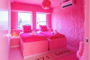 A pink-themed room with two beds, a window, and an air conditioning unit. - Maison Glamsterdam | Amsterdam's Most Unique Stay (Amsterdam)