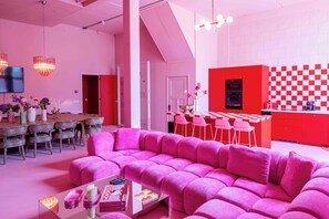 A modern interior with a pink sofa, dining area, kitchen, and a staircase. - Maison Glamsterdam | Amsterdam's Most Unique Stay (Amsterdam)