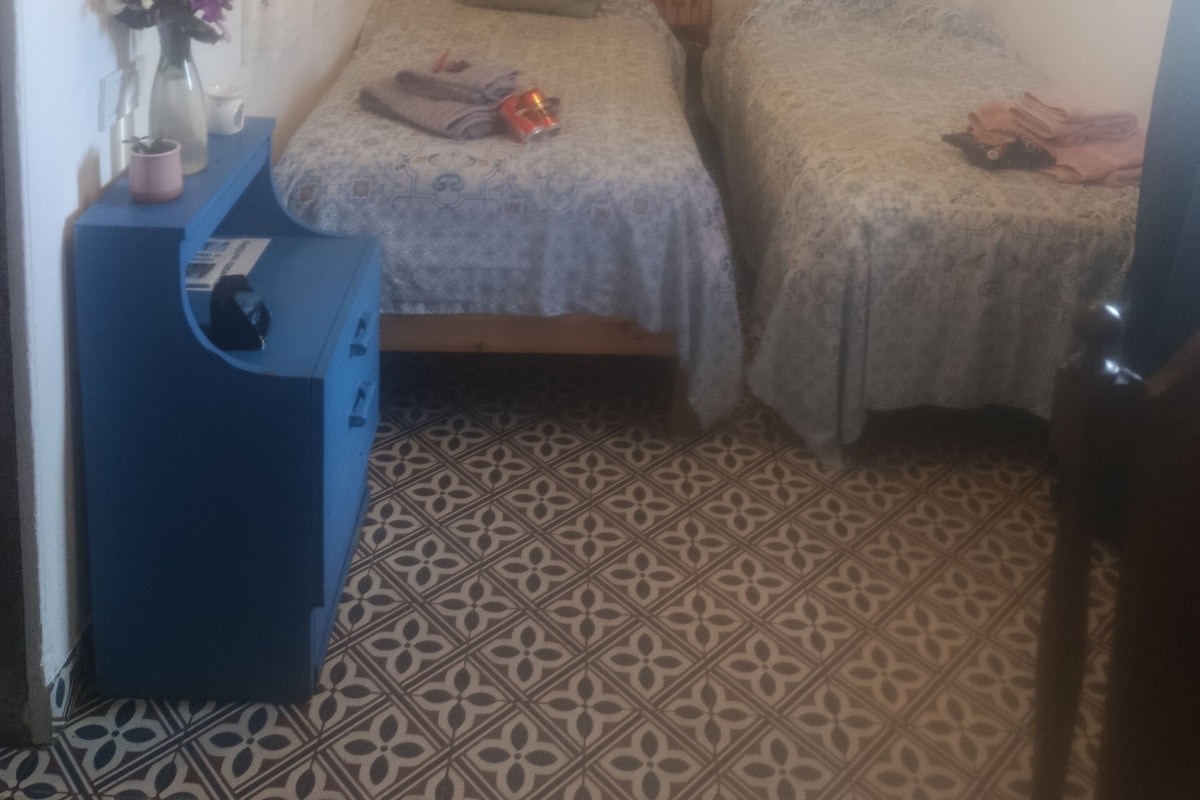 Un dormitorio con dos camas, un aparador azul, un espejo y un adorno de pared.