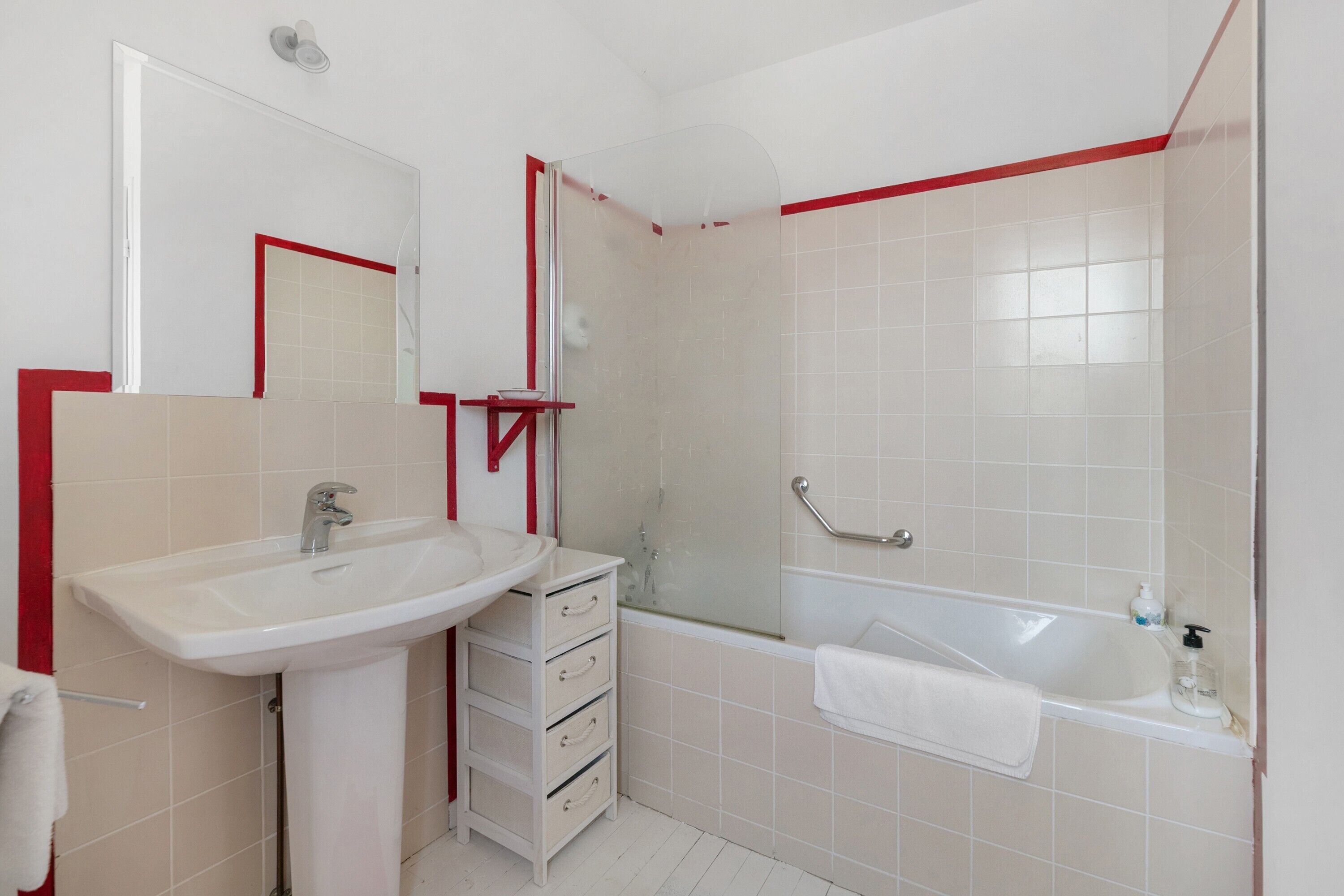 A bathroom with a white sink, a mirror, a glass shower enclosure, and a bathtub.