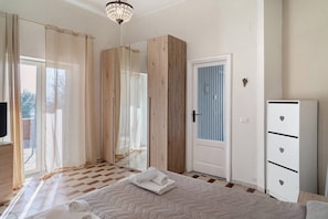 Un dormitorio con cama, armario, televisor y una puerta con ventanal.