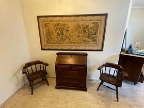 A room with a large framed artwork on the wall, a wooden dresser, and two wooden chairs.