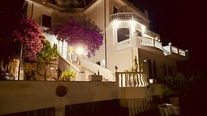 Un edifici gran de diverses plantes amb un balcó i escales que condueixen a l'entrada.